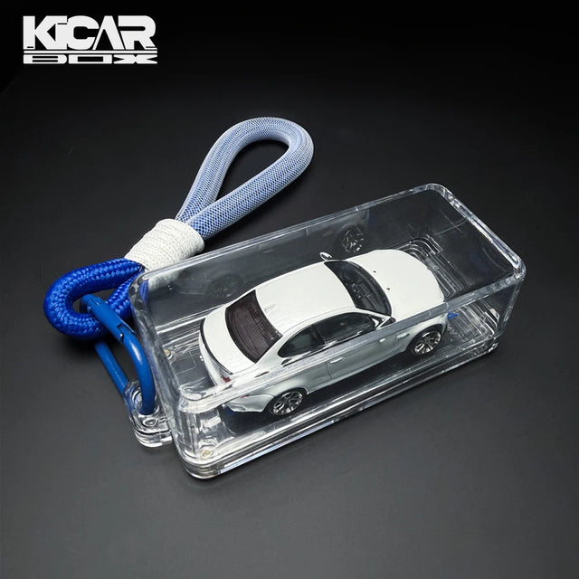 Clear KicarBox display case holding a white 1:64 diecast sports car with a blue lanyard and carabiner